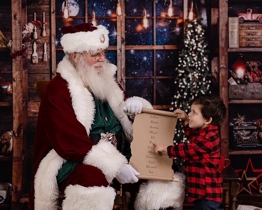 little boy looking at santa pointing to his list